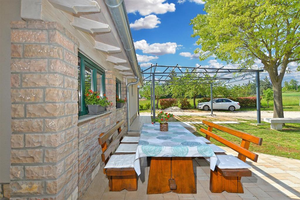 eine Terrasse mit einem Tisch, einer Bank und einem Auto in der Unterkunft House Marta 2157 in Žminj