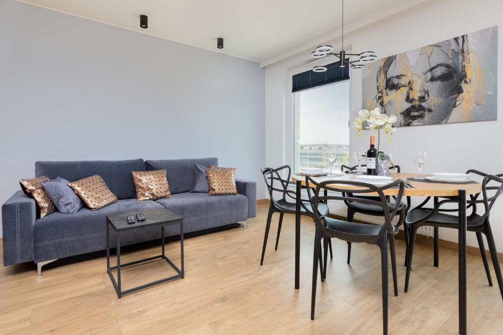 a living room with a couch and a table and chairs at Apartament Przystań Letnica by Renters in Gdańsk