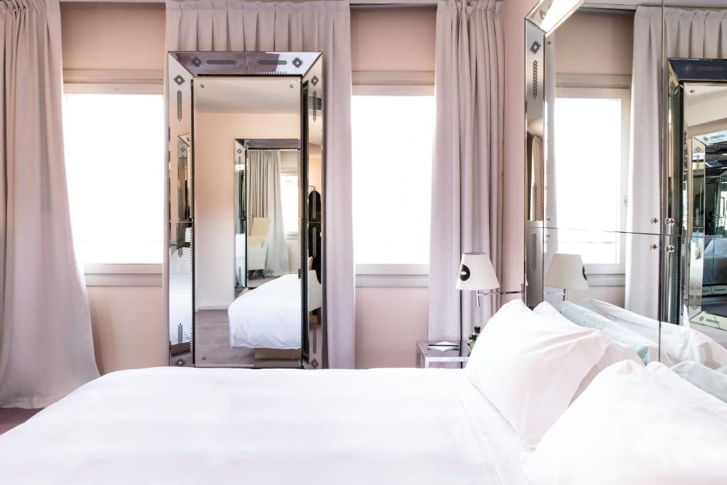 a bedroom with a large white bed and mirrors at Hotel Palazzina Grassi in Venice