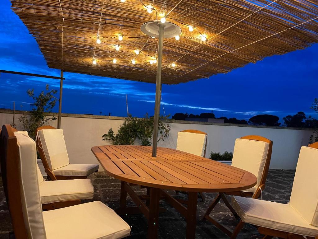 einen Holztisch und Stühle auf einer Terrasse in der Nacht in der Unterkunft Casa di Rosaria - Due appartamenti nel centro storico con giardino sul terrazzo in Depressa