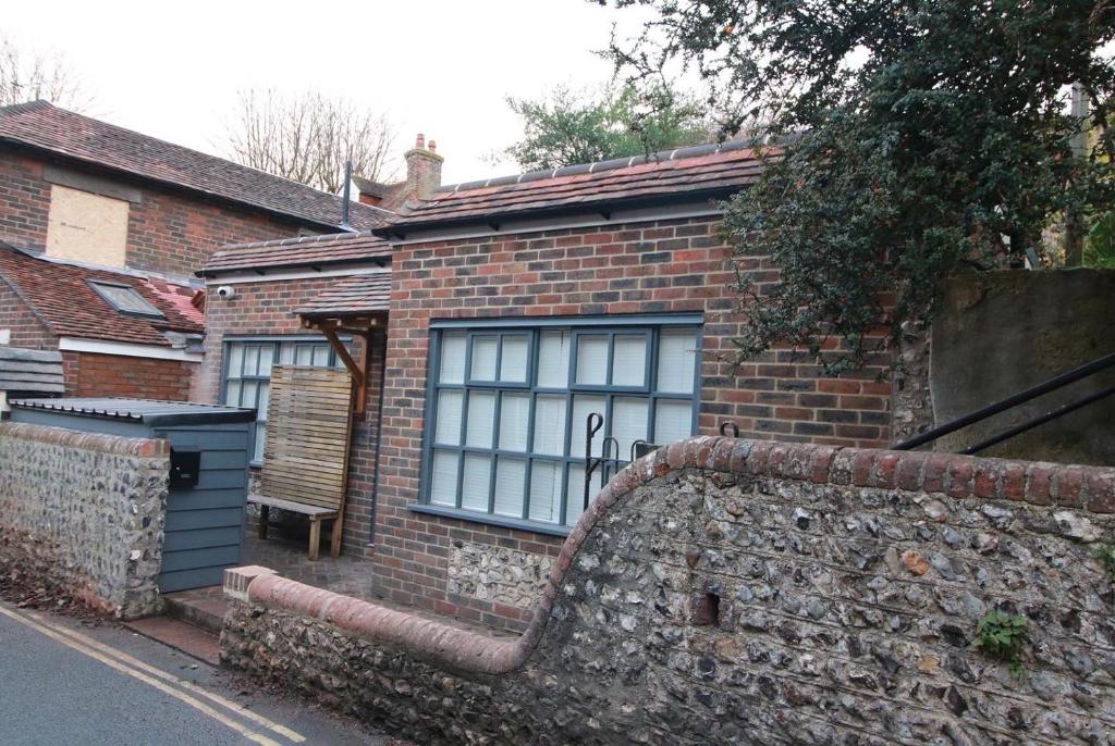 a brick house with windows and a stone wall at Alfriston Lodge By Air Premier in Alfriston