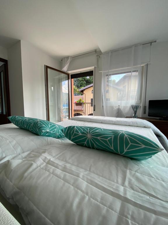 ein großes weißes Bett mit grünen Kissen darauf in der Unterkunft Appartamento Cannella in Bellagio