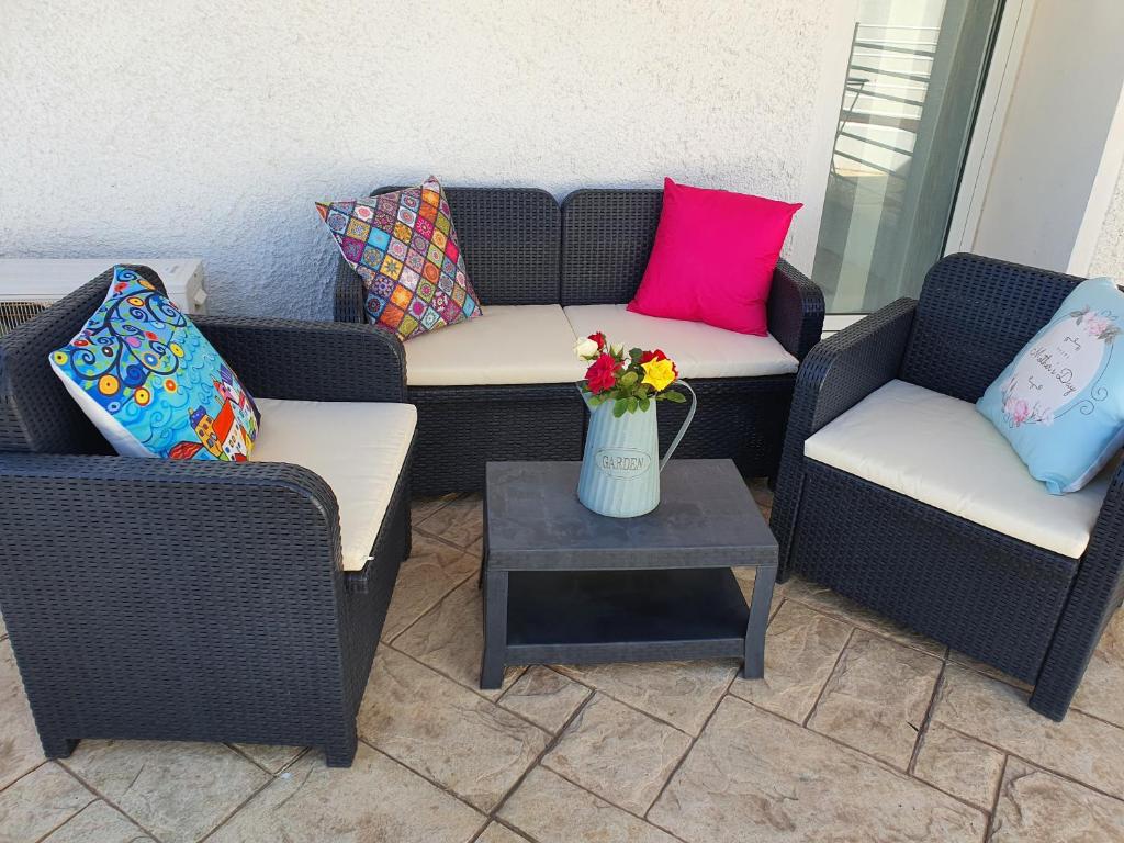 2 Stühle und ein Tisch mit Kissen und eine Vase mit Blumen in der Unterkunft JANAS Country House in Castelsardo