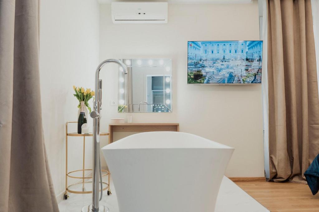 ein Badezimmer mit einer weißen Badewanne und einem Spiegel in der Unterkunft Cesare ai Cavalieri Suites in Rom