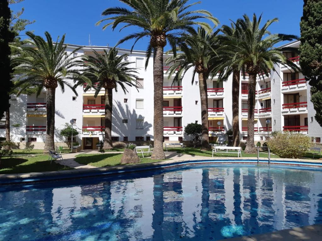 una piscina frente a un edificio con palmeras en Córcega Palm Beach Salou - Piscina y Jardín, en Salou