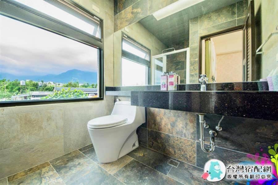 a bathroom with a toilet and a window at 花蓮漫漫時光電梯包棟民宿 in Hualien City