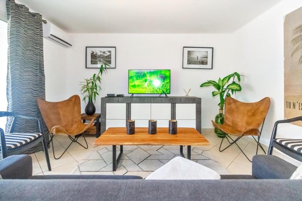 sala de estar con TV y sillas en Safari - Apt rénové proche des Roches Noires - Saint Gilles les Bains, en Saint-Gilles-les-Bains