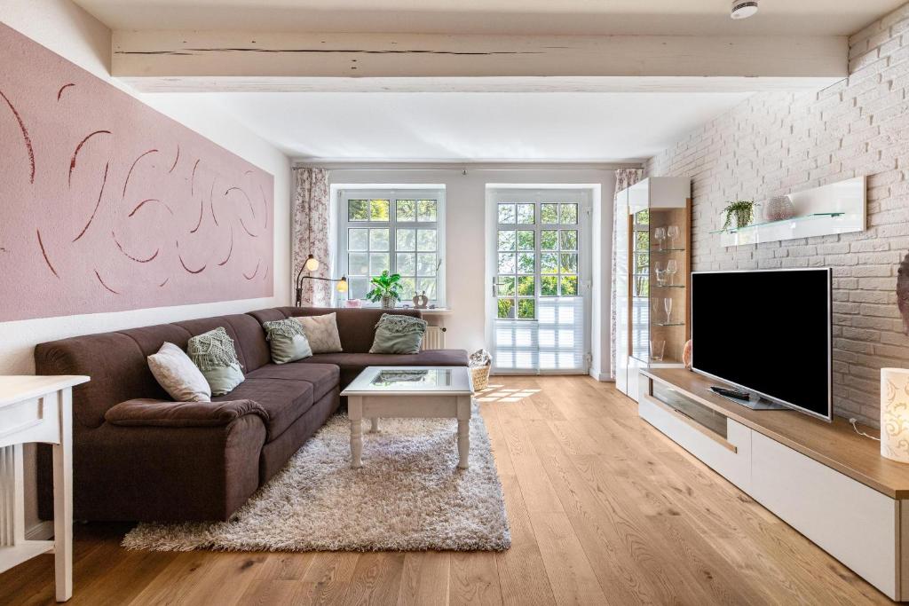 a living room with a couch and a tv at Denkerhof Fewo Blume des Lebens in Reußenköge