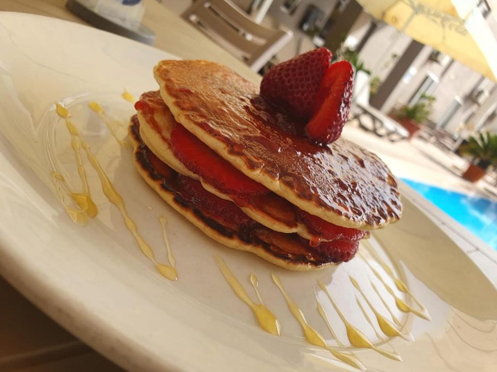 a stack of pancakes with strawberries on a plate at Sensi Hotel in Marsaskala