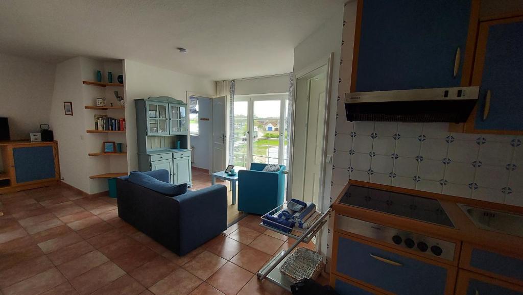 un soggiorno con divano blu e una cucina di Ferienwohnung Drachen ad Alt Reddevitz