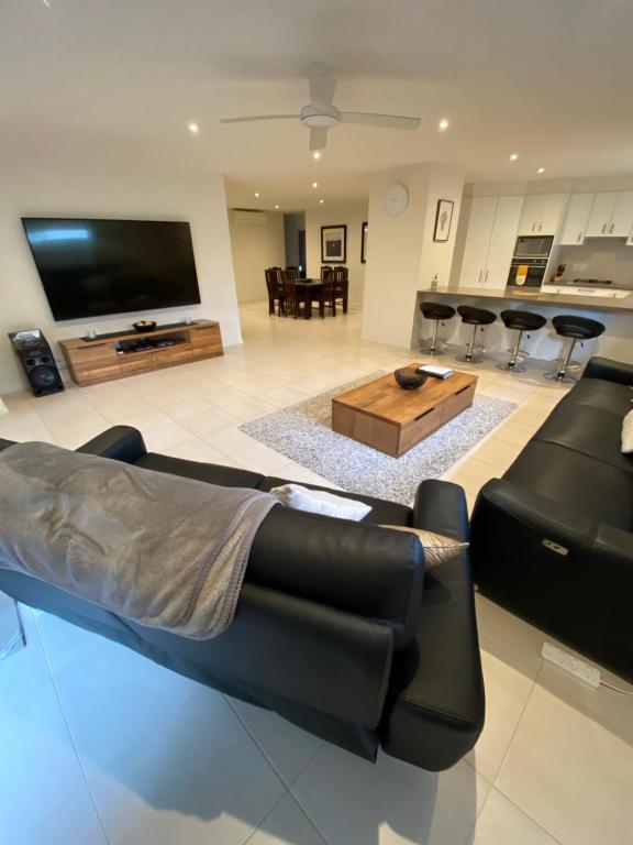 a living room with a black couch and a table at Sun-lovers Beach House - Walk to beach/shops! in Rosebud