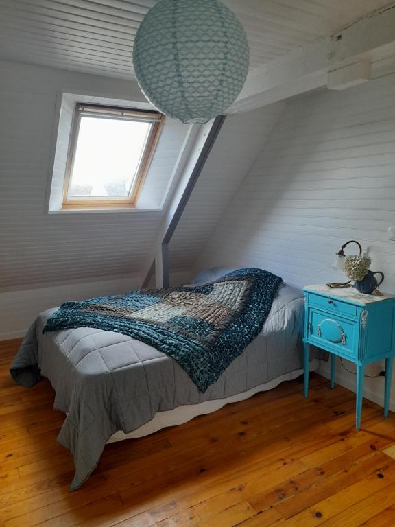 1 dormitorio con 1 cama con mesita de noche azul y ventana en Aux portes de locronan en Quéménéven