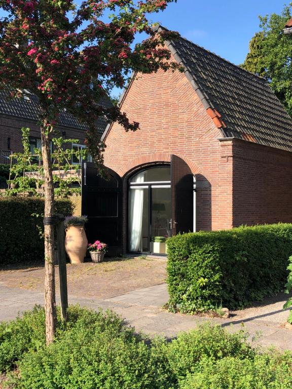 een rood bakstenen huis met een raam en een boom bij Maison de l'Epée in Emmeloord