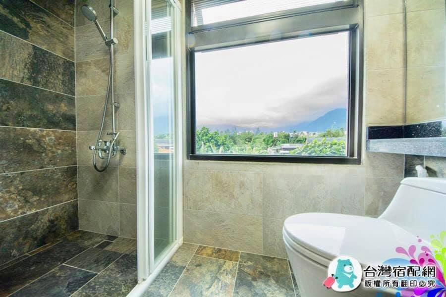 a bathroom with a shower and a toilet and a window at 花蓮漫漫時光電梯包棟民宿 in Hualien City