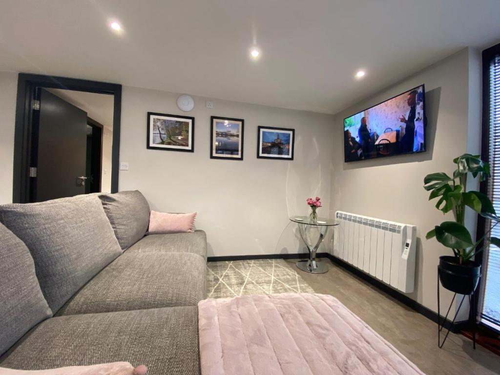 a living room with a couch and a tv at The Courtyard Apartment in Brampton