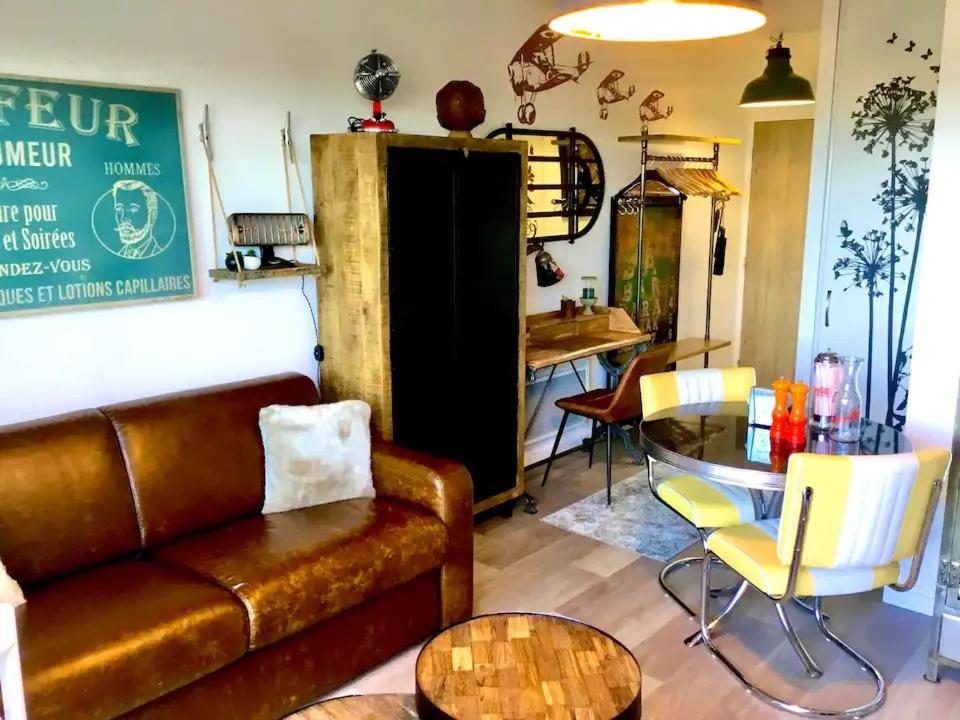 a living room with a couch and a table at Studio neuf,vintage,terrasse,wifi ,excellence face mer in Saint-Hilaire-de-Riez