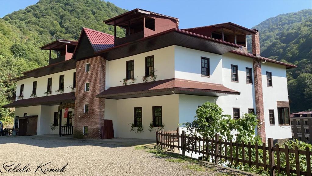 uma casa grande com uma cerca em frente a uma montanha em Şelale Konak Çavuş'un Yeri em Rize