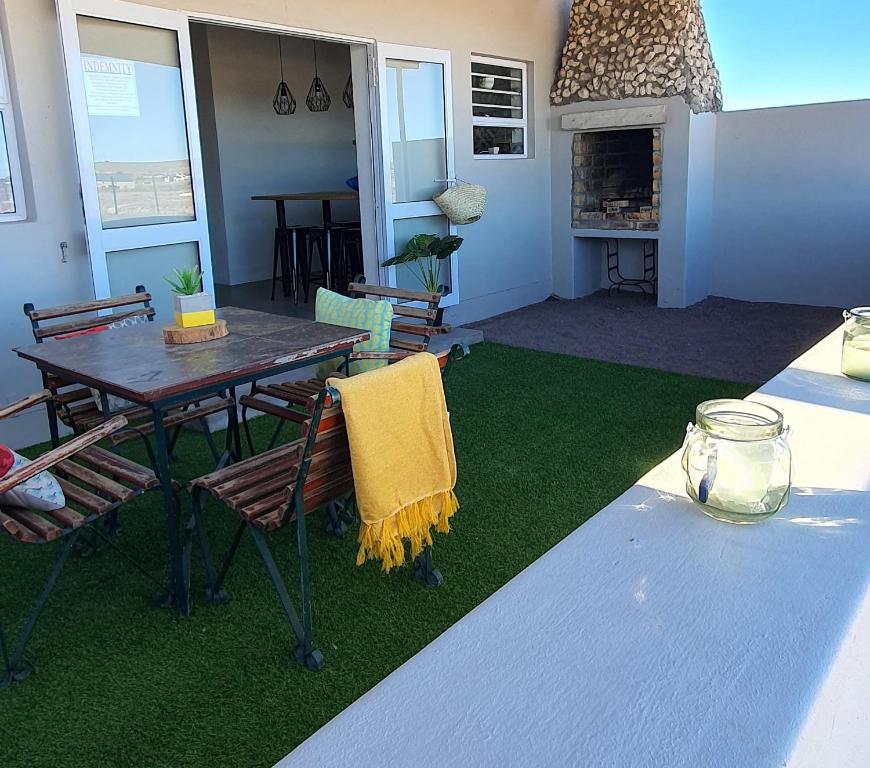 a patio with a table and chairs and a fireplace at Bellas Cottage in Langebaan