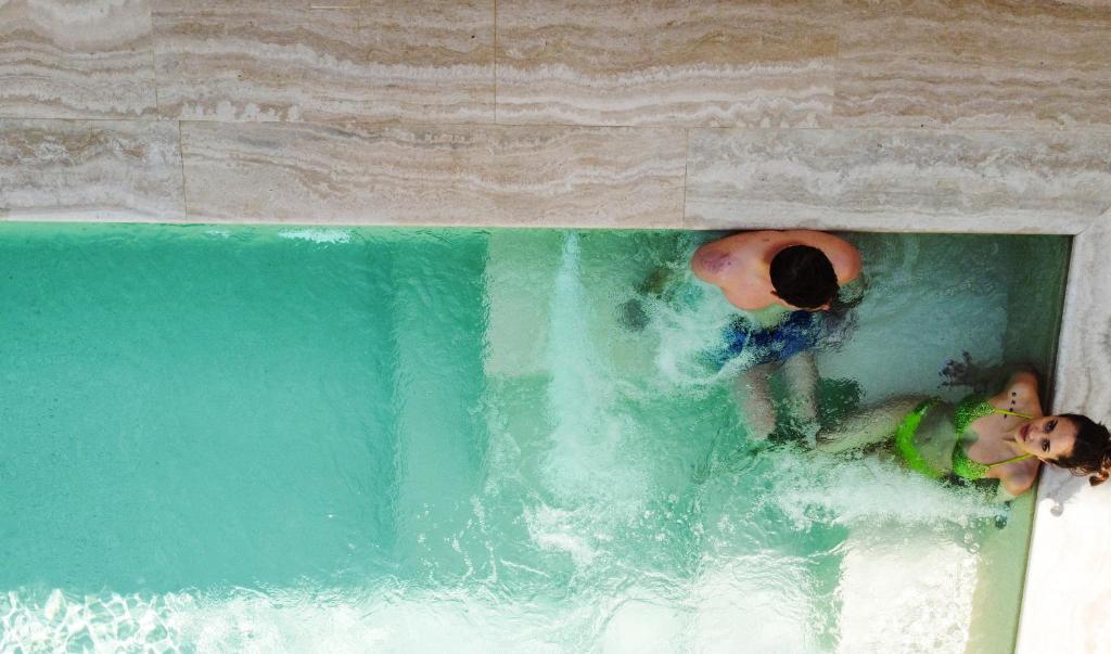 two people in the water in a swimming pool at Hotel Baglio Di Scopello in Scopello