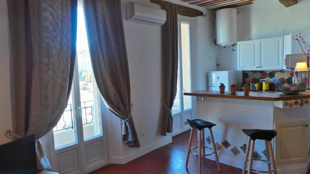 a kitchen with a counter and stools next to a window at Hotel Relais Du Postillon in Antibes