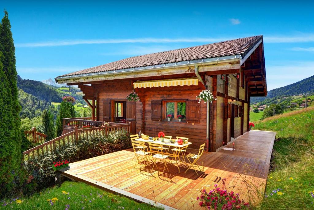 a small wooden cabin with a table on a deck at Chalet Les Houlottes - OVO Network in Manigod