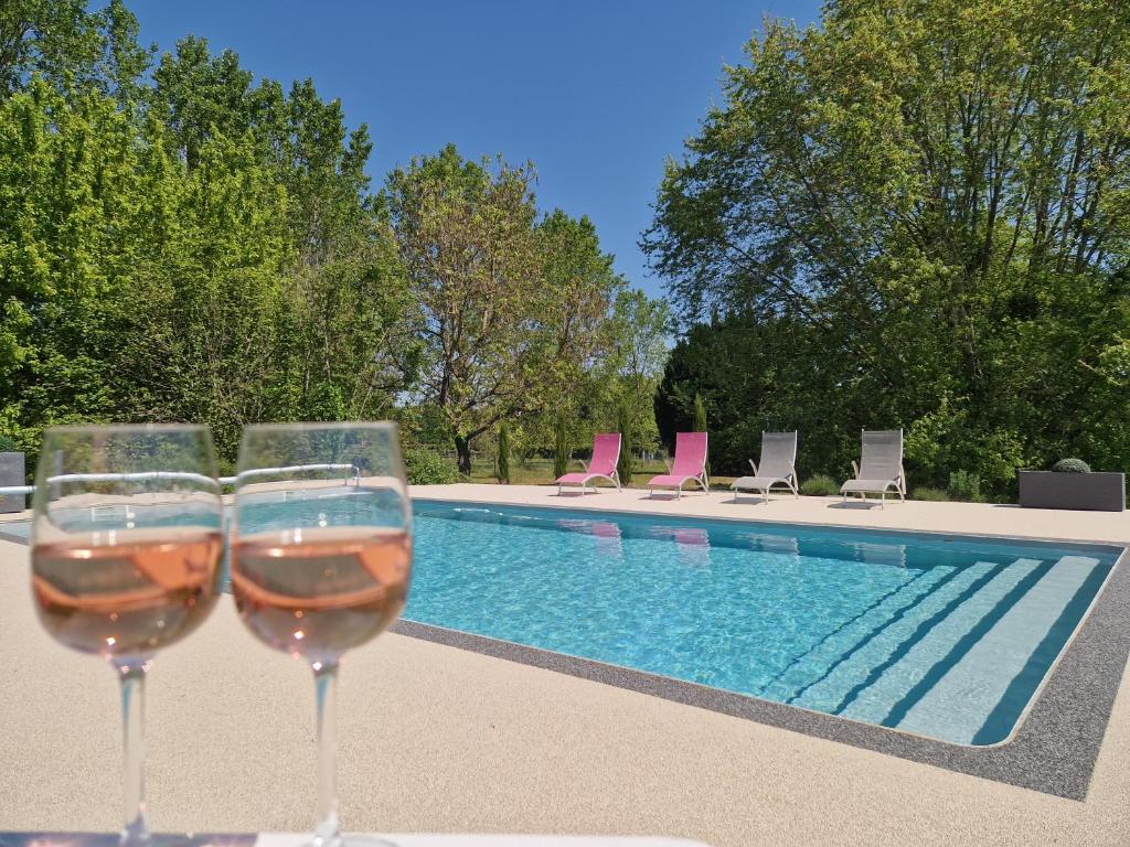 twee glazen wijn naast een zwembad bij Maison/gîte-6 km de Tours in La Membrolle-sur-Choisille