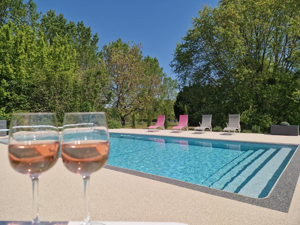 ラ・マンブロル・シュル・ショワジーユにあるMaison/gîte-6 km de Toursのスイミングプールの隣に座るワイン2杯