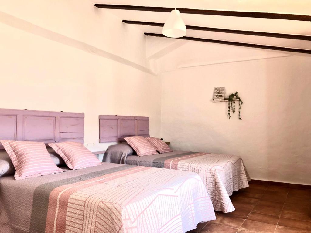 duas camas num quarto com lençóis cor-de-rosa e brancos em Casa de campo con maravillosas vistas, bbq y piscina em Ronda