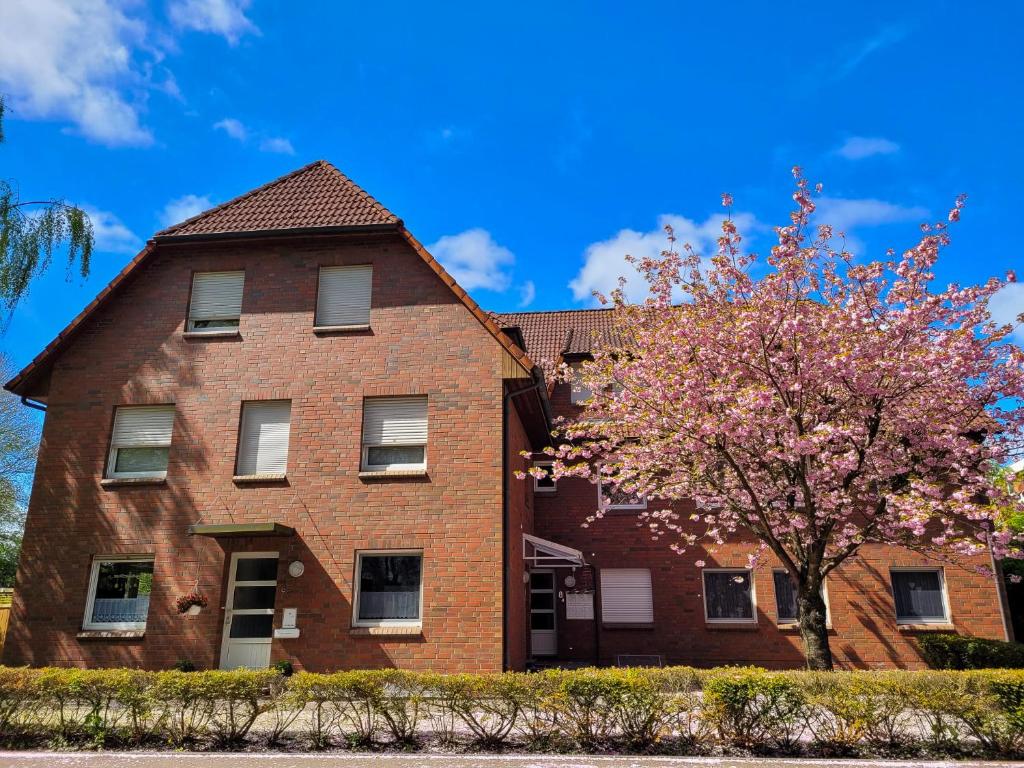 un bâtiment en briques avec un arbre devant lui dans l'établissement Ferienwohnung Nordseebutze, à Esens