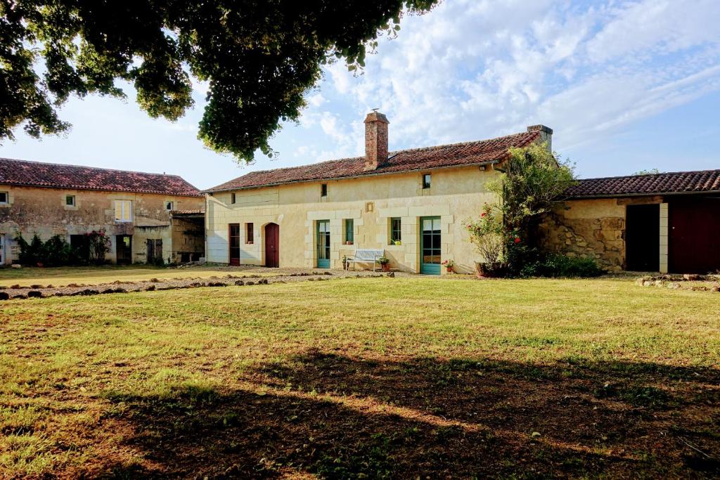 une vieille maison avec une cour d'herbe devant elle dans l'établissement Closerie Les Roches - Charming and spacious 2 bedroom cottage, à Bouillé-Loretz