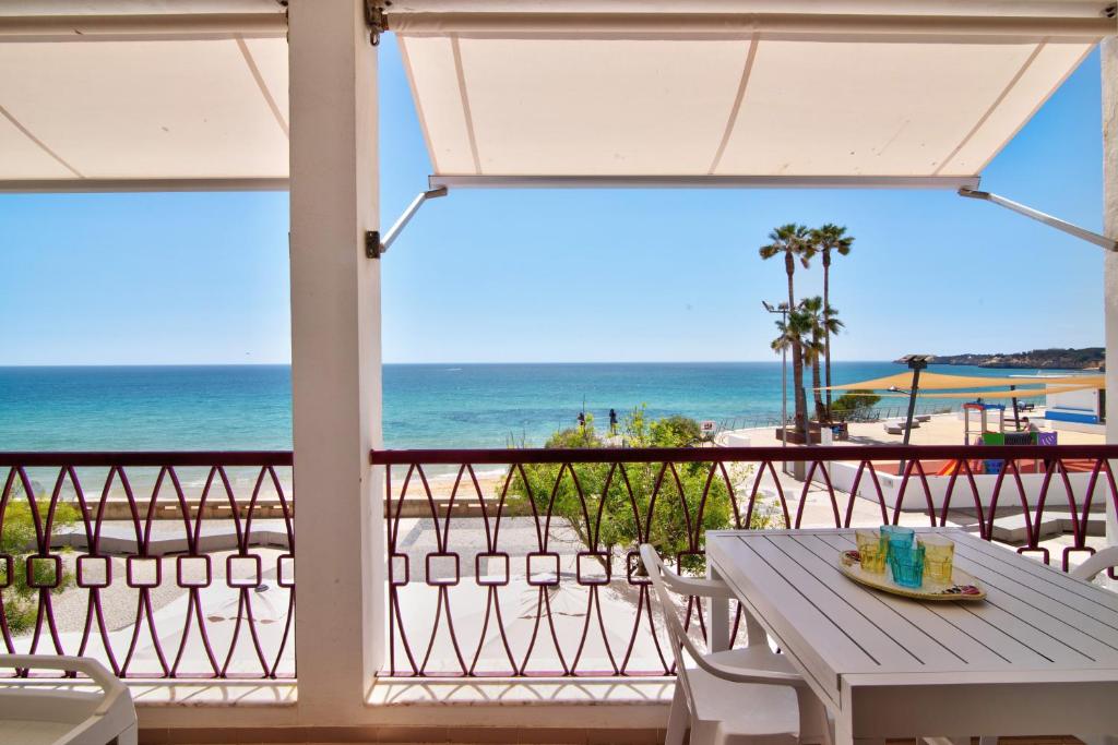 a table and chairs on a balcony with the beach at Apartamento beira mar in Armação de Pêra