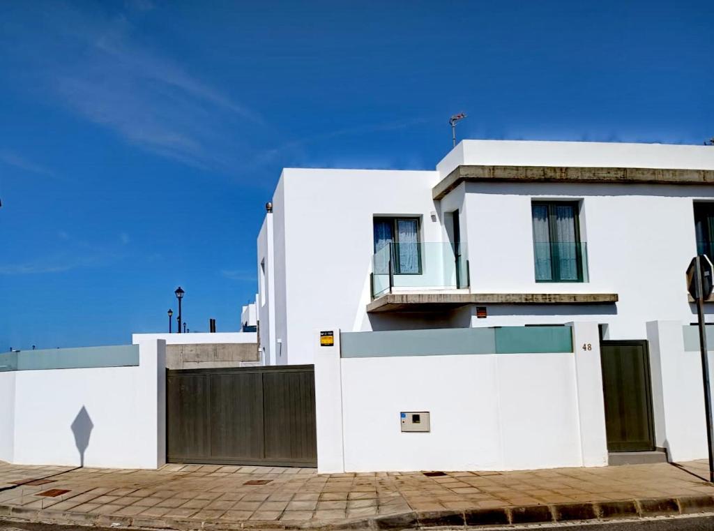 a white building with a gate in front of it at Arrecife exclusive beach house in Arrecife