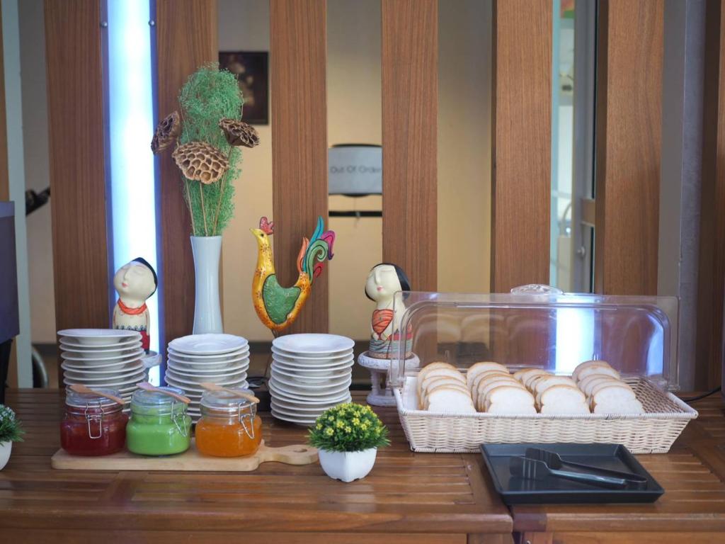 A breakfast buffet table offers bread, spreads, plates, and decorative displays.