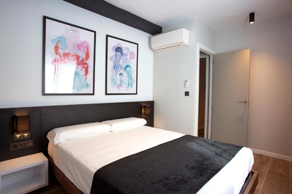 una camera con un letto e due quadri appesi al muro di Apartamentos La Espadaña a Rota