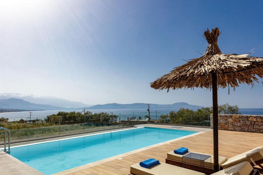 a swimming pool with a straw umbrella and chairs next to a swimming pool at Aristotelis Residence in Petres