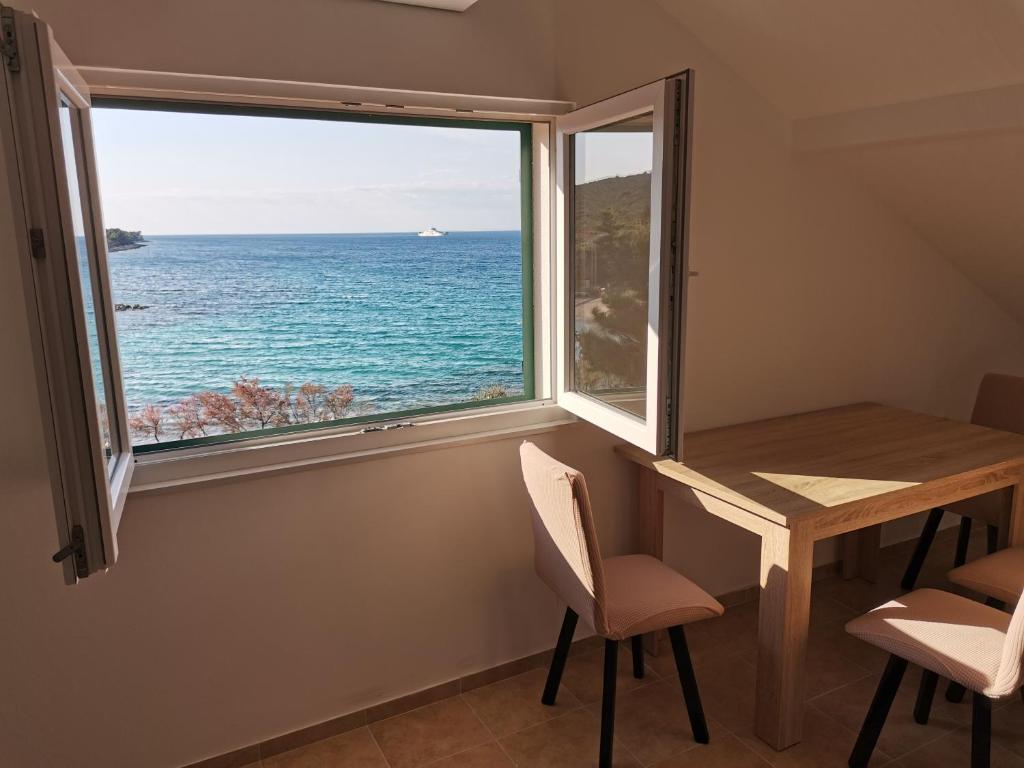 Habitación con mesa y ventana con vistas al océano. en Apartment Porat 2 en Ugljan