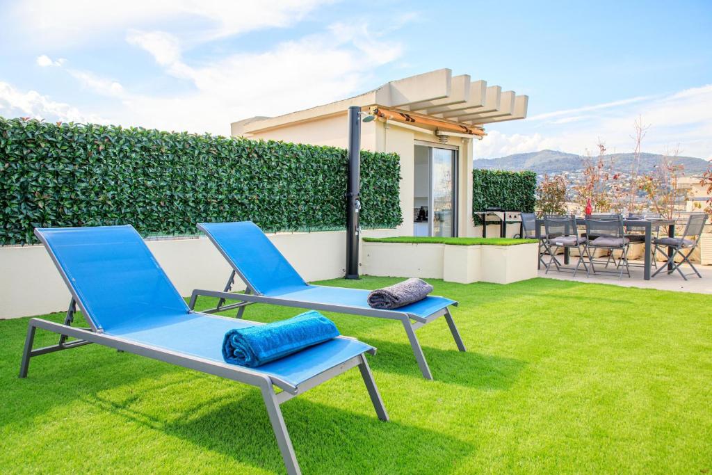 deux chaises bleues assises sur l'herbe dans une cour dans l'établissement Duplex Avec Rooftop Et Vue Mer Panoramique - Riou De L'argentière, à Mandelieu-la-Napoule