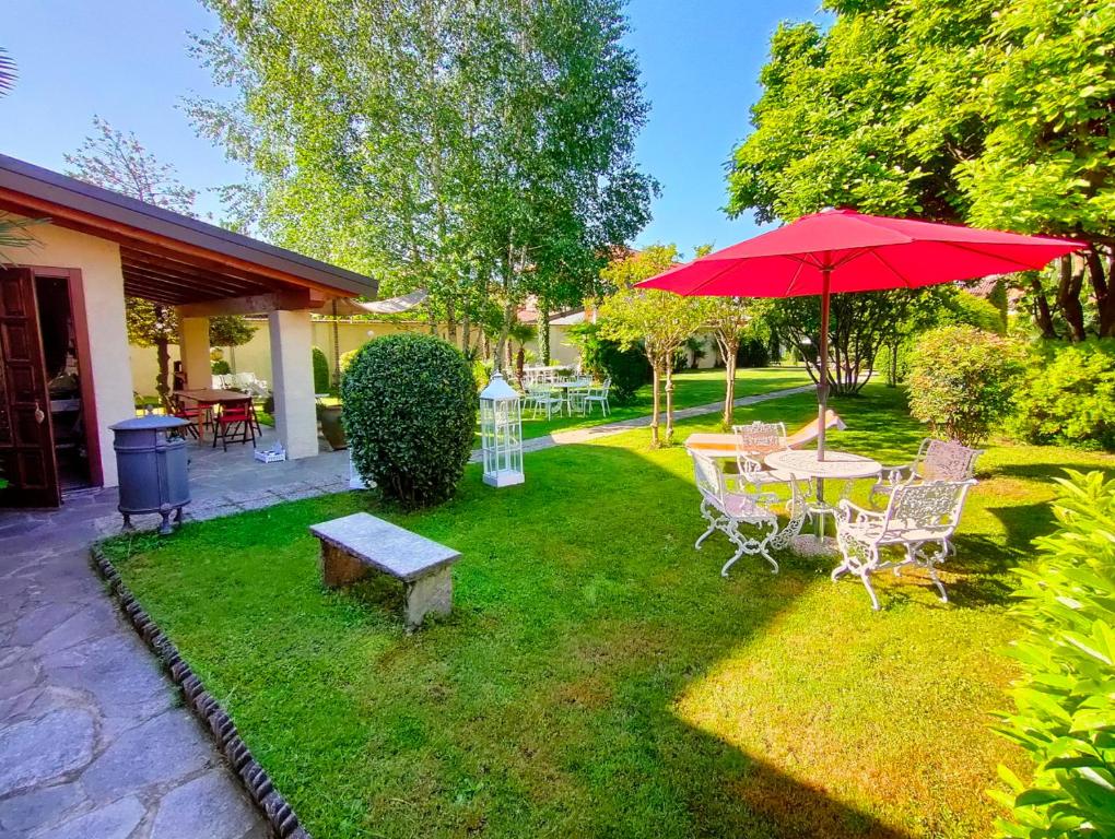 een patio met een tafel en een rode parasol bij Villa DaVinci in Verbania