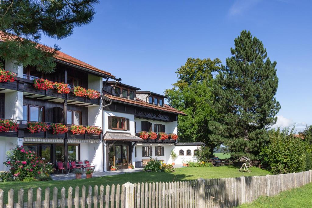 ein Haus mit Blumen auf den Balkonen und einem Zaun in der Unterkunft Pension Heim in Seeg