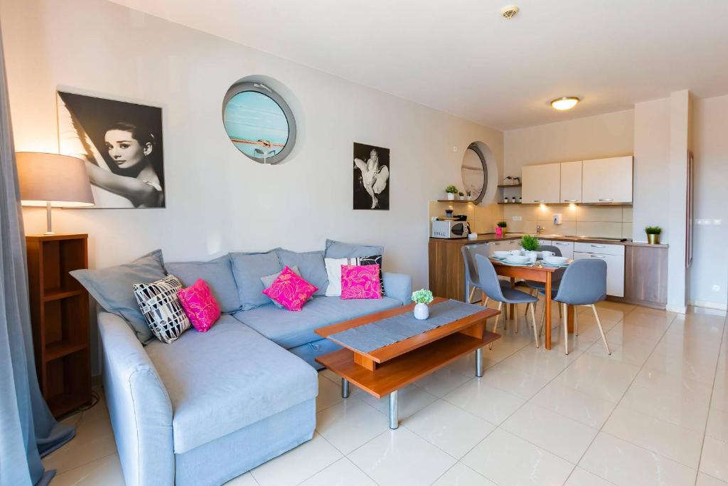 a living room with a blue couch and a table at VacationClub – Diune Apartment 14 in Kołobrzeg