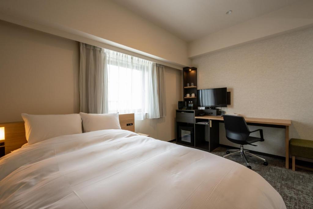 a hotel room with a bed and a desk with a computer at Hotel Kanazawa in Kanazawa