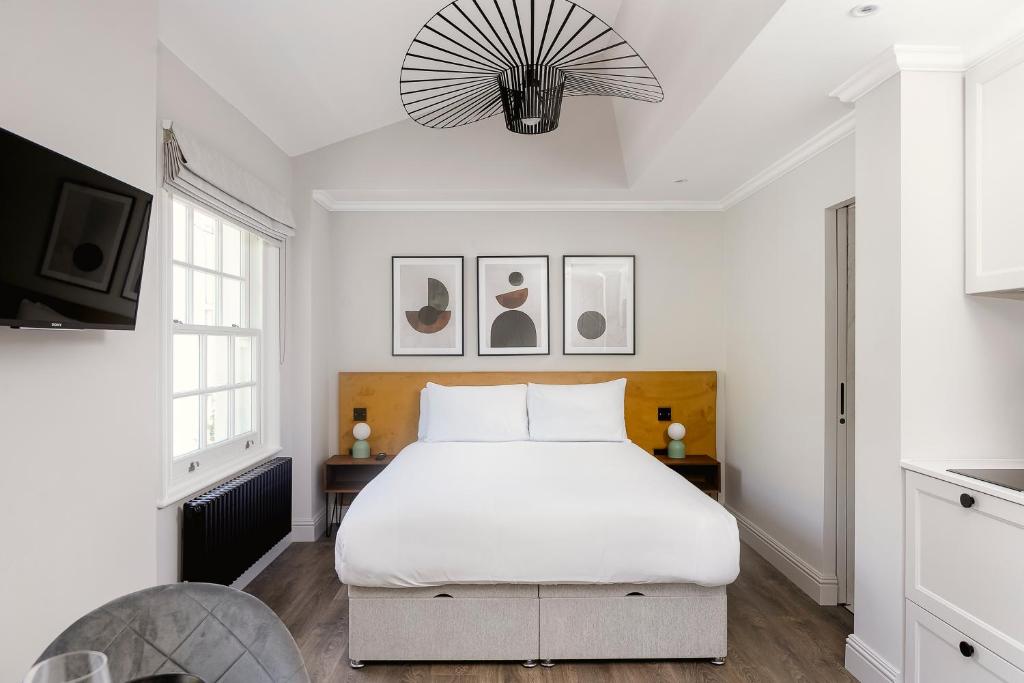 a white bedroom with a large bed and a tv at PenthouseStays Chelsea - Luxury King / Queen Bed Studios - near King's Road in London