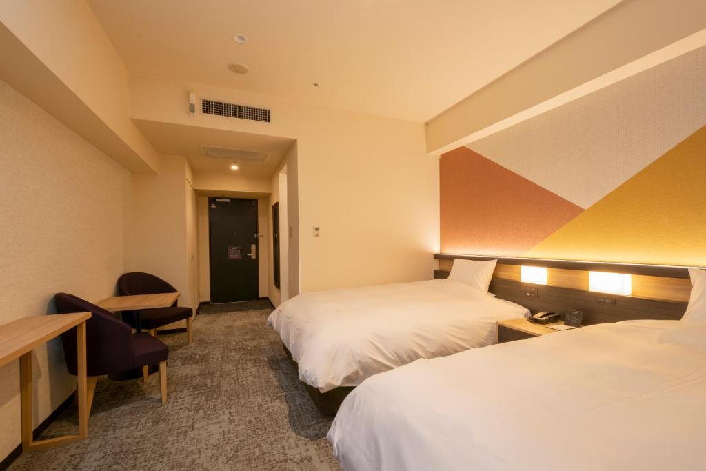 a hotel room with two beds and a desk at Hotel Kanazawa in Kanazawa