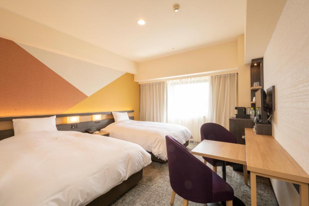 a hotel room with two beds and a desk at Hotel Kanazawa in Kanazawa