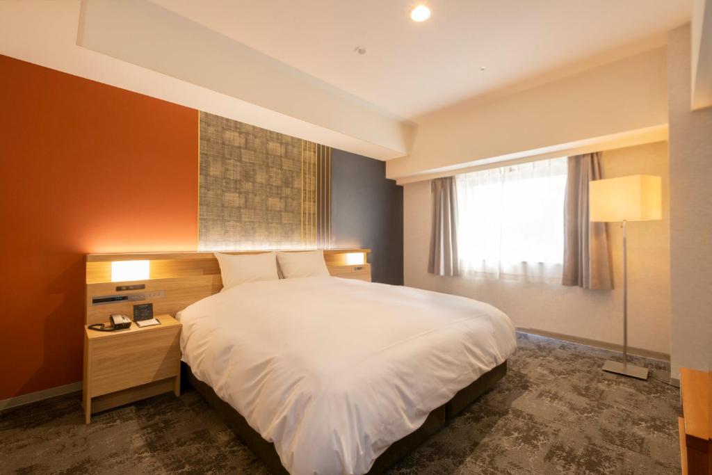 a bedroom with a white bed and a window at Hotel Kanazawa in Kanazawa