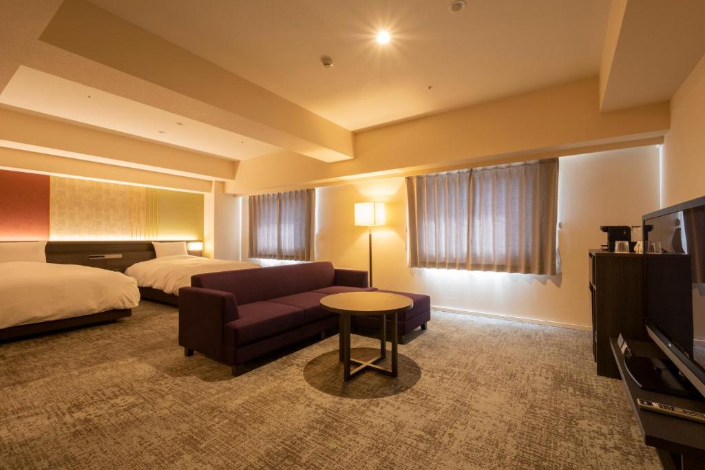 a hotel room with a bed and a couch and a tv at Hotel Kanazawa in Kanazawa