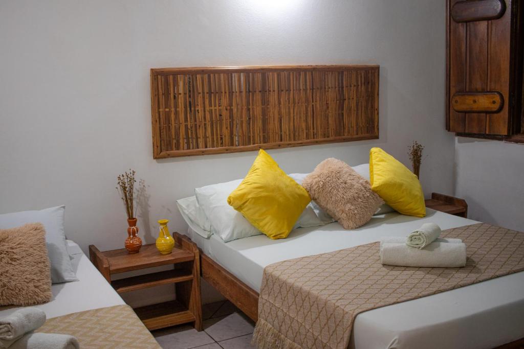 a bedroom with two beds with yellow and white pillows at Pousada Lanai in Itacaré