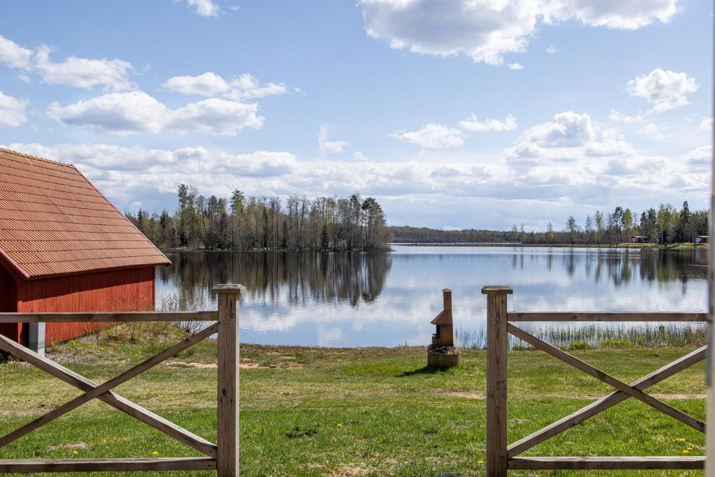 un granero y una cerca junto a un lago en Holiday house with terrace and views of Lake Hangasjon en Hamneda