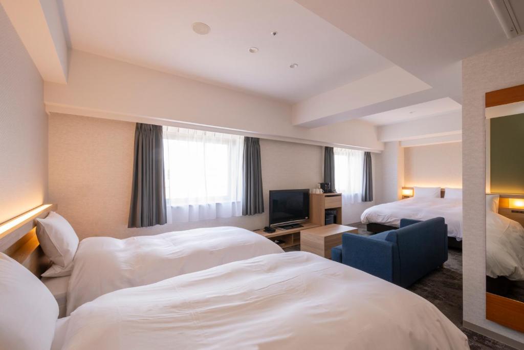 a hotel room with two beds and a television at Hotel Kanazawa in Kanazawa