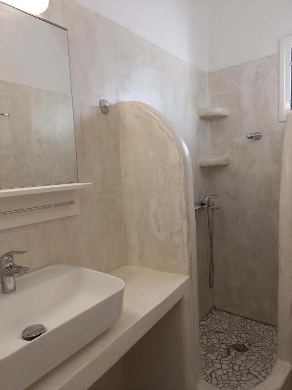 a bathroom with a sink and a shower with a mirror at Marianna Studios in Donoussa